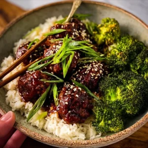 Sticky Mongolian beef meatballs served on a plate with sauce and garnish.