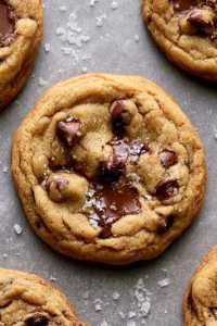 Chewy chocolate chip cookies on a plate with a glass of milk